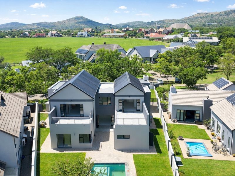 Aerial view of a modern residential property featuring solar panels, private swimming pools, balconies, and well-maintained garden spaces within a scenic estate.