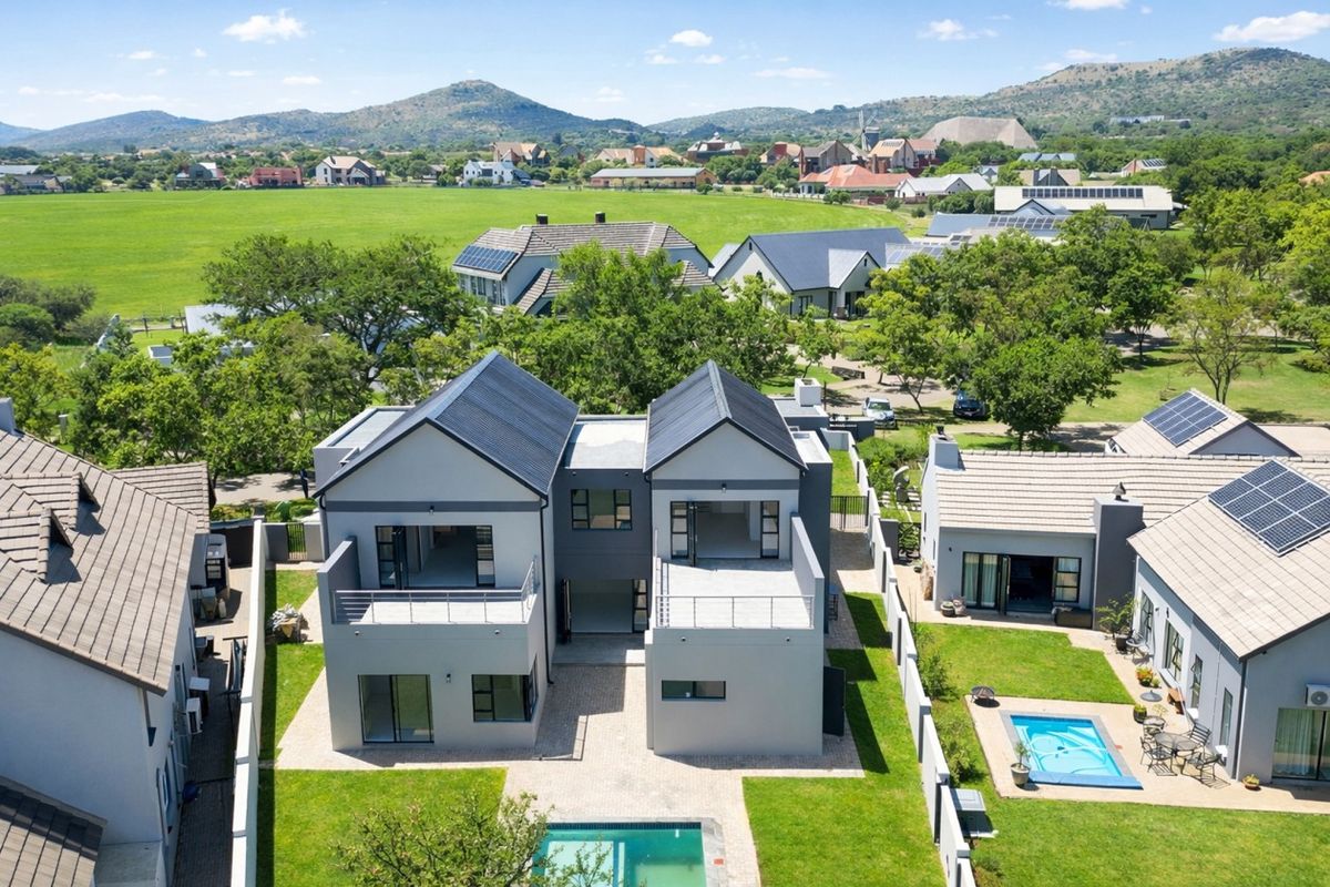 Aerial view of a modern residential property featuring solar panels, private swimming pools, balconies, and well-maintained garden spaces within a scenic estate.