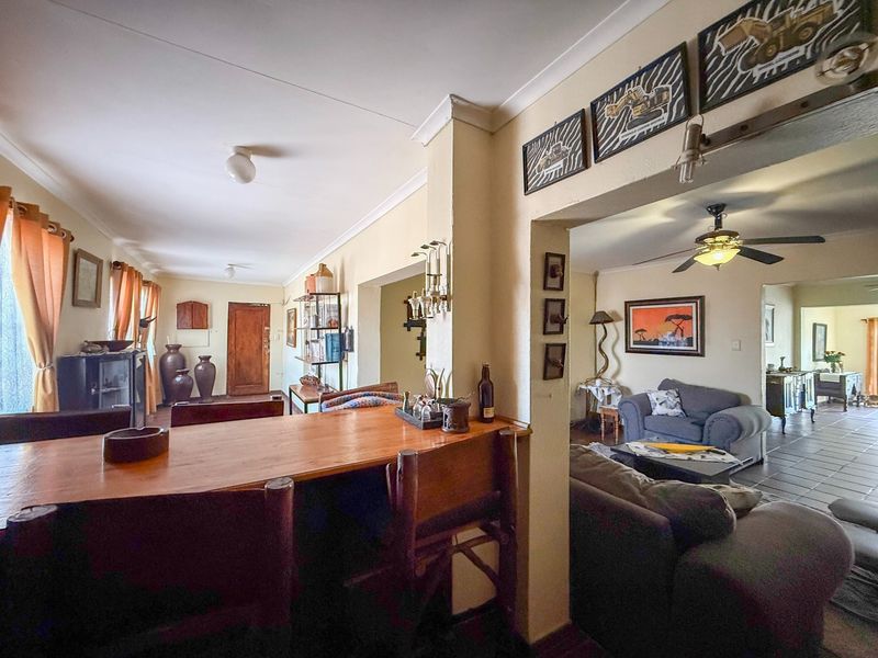 Spacious open-plan living and dining area featuring tiled flooring, coving, and a ceiling fan, connecting multiple living spaces within the home.