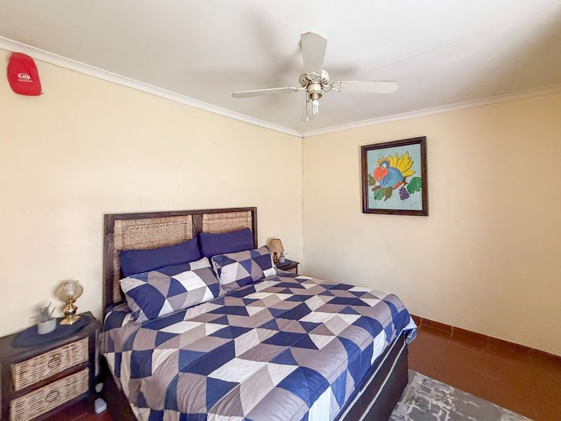 A standard bedroom featuring tiled flooring and a ceiling fan, with neutral wall finishes.