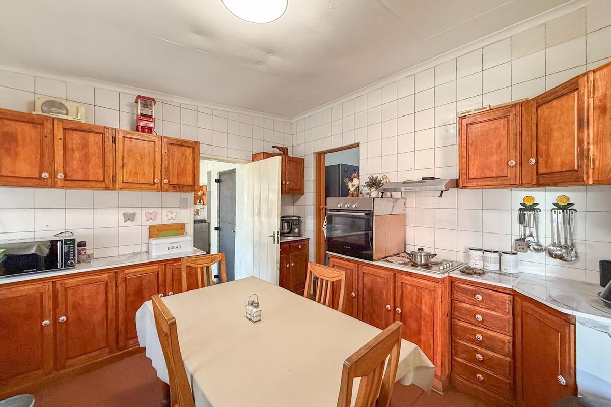 A functional kitchen featuring traditional wooden cabinetry, tiled splashbacks, and built-in cooking appliances, offering a classic layout with potential for modern updates.