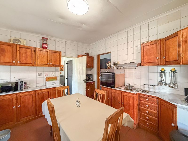 A functional kitchen featuring traditional wooden cabinetry, tiled splashbacks, and built-in cooking appliances, offering a classic layout with potential for modern updates.