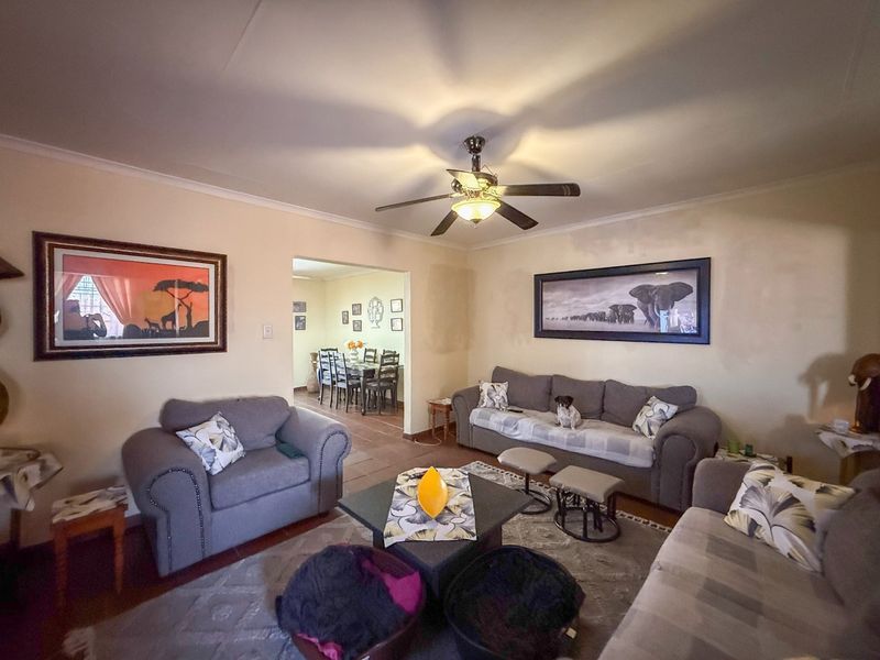 Open-plan living area featuring a ceiling fan and tiled flooring, with an adjacent dining space visible through the archway.
