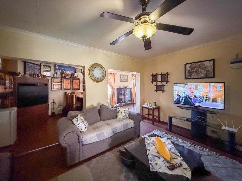 A comfortable living room featuring a ceiling fan and coved cornicing, providing a functional and lived-in space for relaxation.