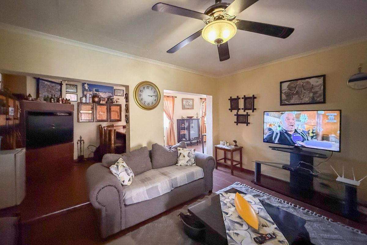 A comfortable living room featuring a ceiling fan and coved cornicing, providing a functional and lived-in space for relaxation.