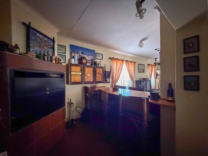 A rustic bar area featuring a built-in counter, cabinetry, and a tiled fireplace, offering a cozy space for entertainment.