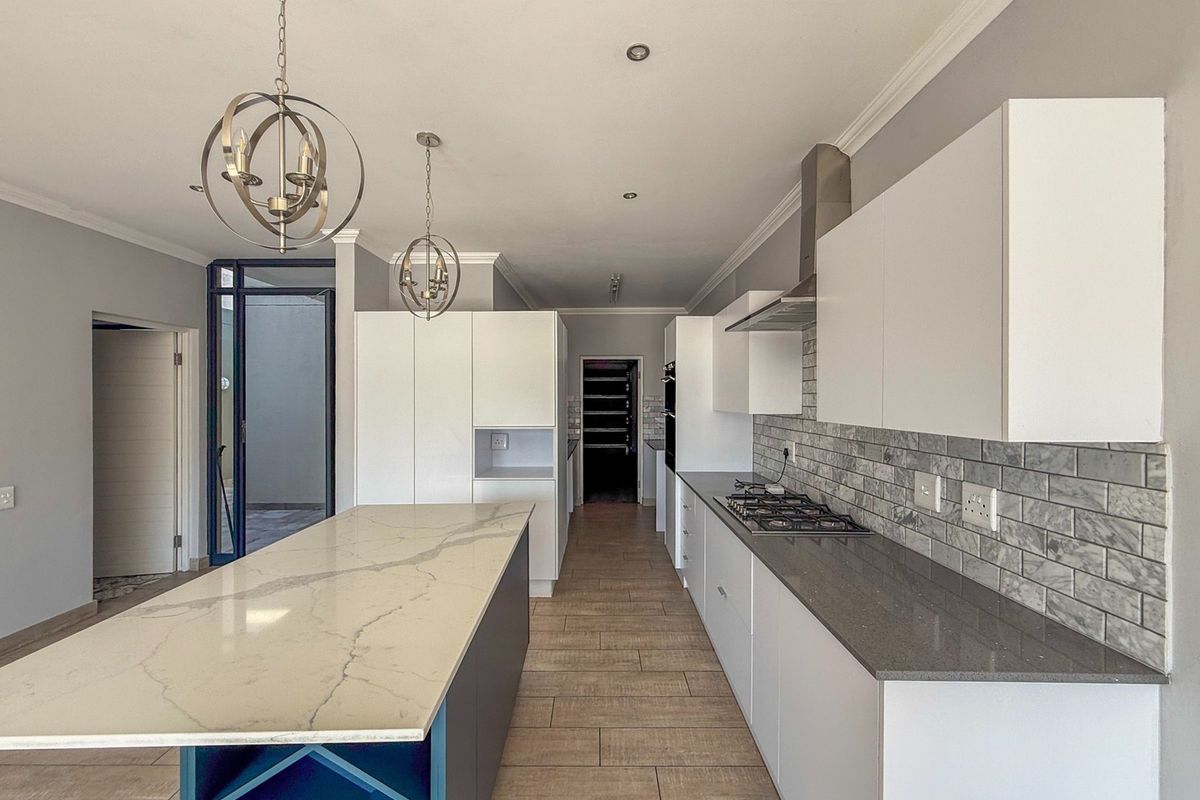 Modern kitchen featuring a large central island with stone countertops, gas hob, subway tile backsplash, and ample built-in cabinetry.