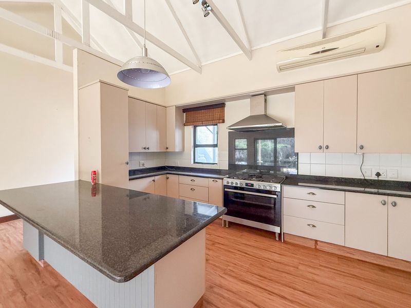Spacious kitchen featuring granite countertops, built-in cabinetry, a gas stove with extractor fan, and vaulted ceilings, offering a functional and bright cooking space.