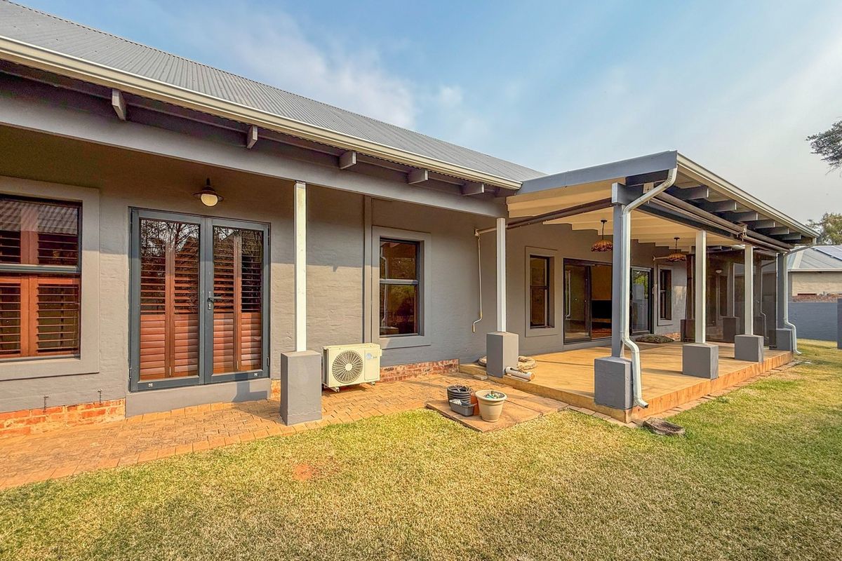 Rear view of the house featuring a covered timber deck, brick paved patio area, and direct access through french and sliding glass doors.