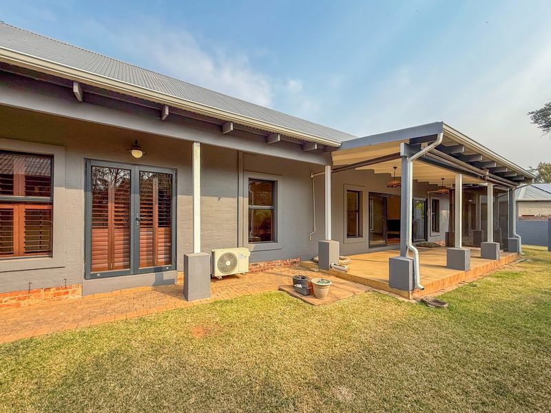 Rear view of the house featuring a covered timber deck, brick paved patio area, and direct access through french and sliding glass doors.