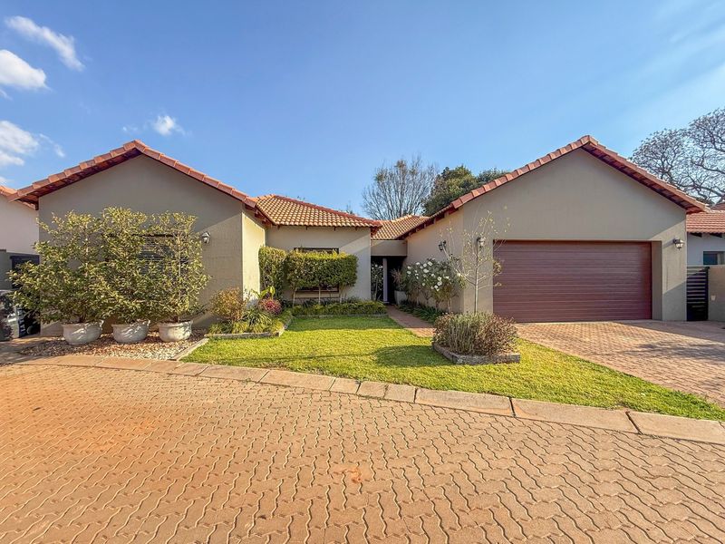 A well-maintained single-story residential property featuring a tiled roof, paved driveway, integrated garage, and a neat front garden.