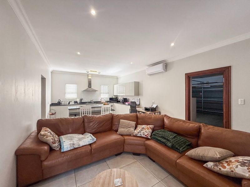 Spacious open-plan living area featuring a modern kitchen with sleek cabinetry, tiled floors, and integrated air conditioning, seamlessly connecting to the lounge space.