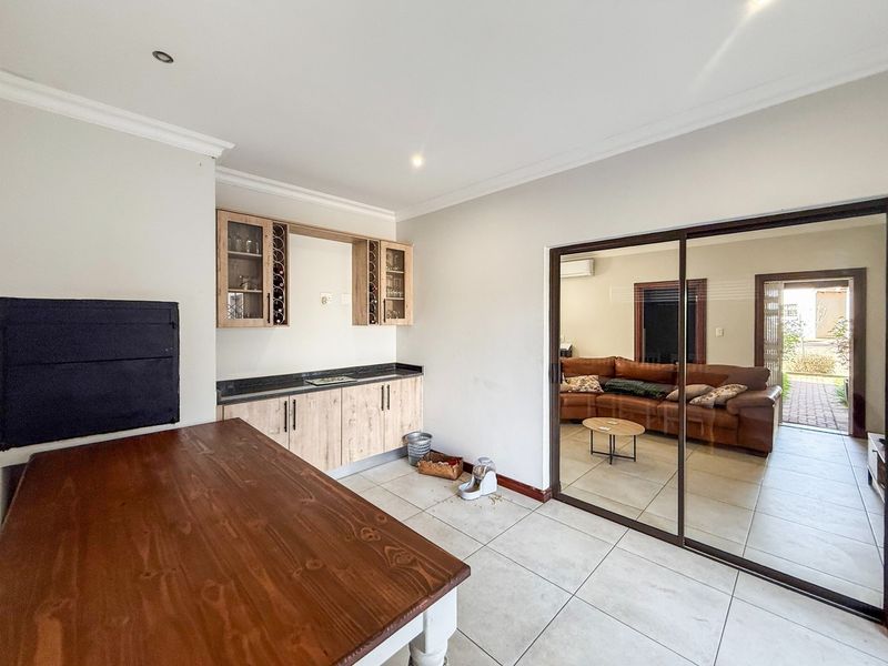 A functional bar area featuring built-in cabinetry, granite countertops, and a wine rack, with direct access to an adjacent living space via sliding glass doors.