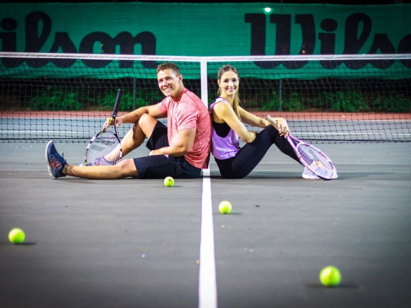 A well-maintained tennis court featuring a standard net and perimeter fencing, suitable for recreational sports and outdoor activities.