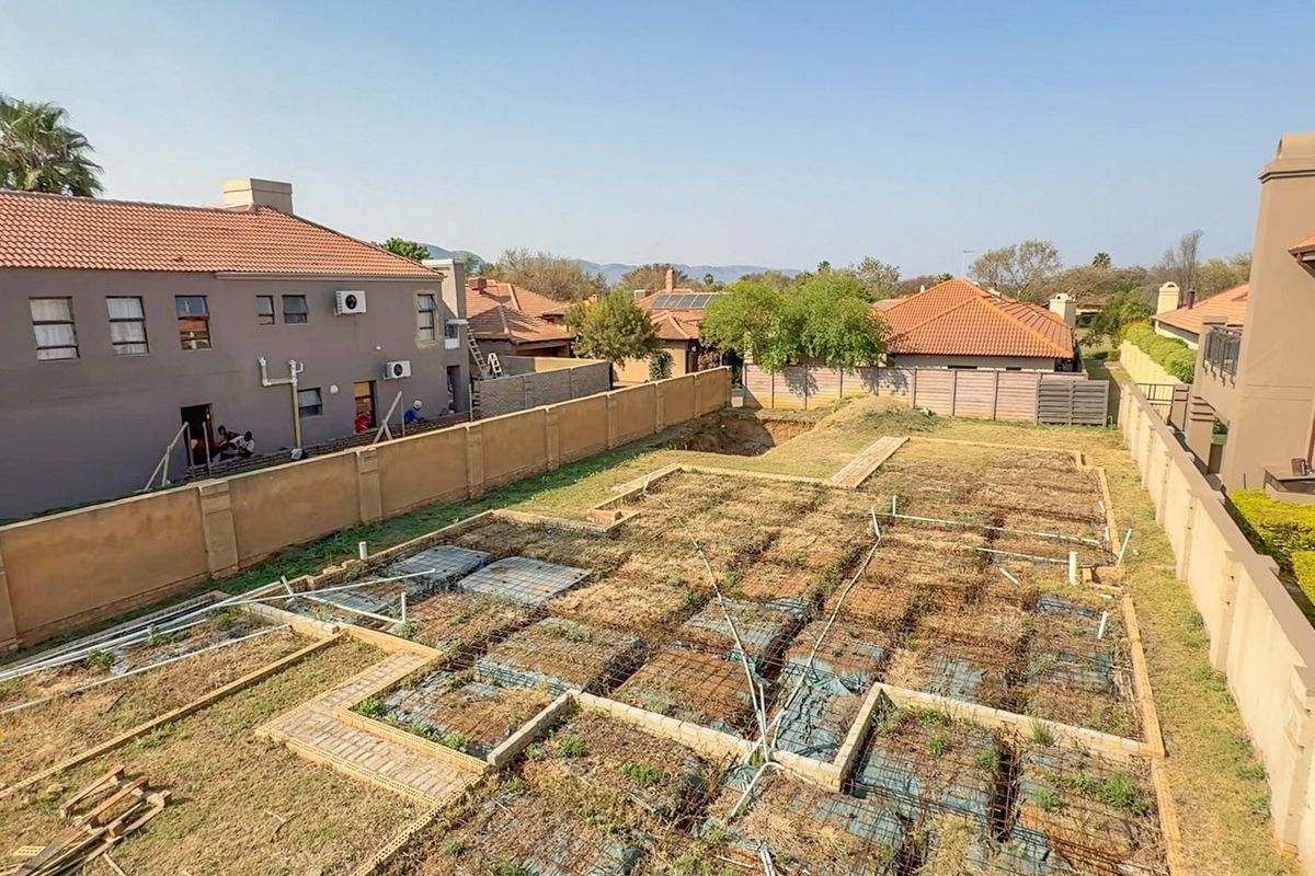 Aerial view of a residential vacant land plot featuring an unfinished foundation slab with exposed reinforcement and perimeter boundary walls.