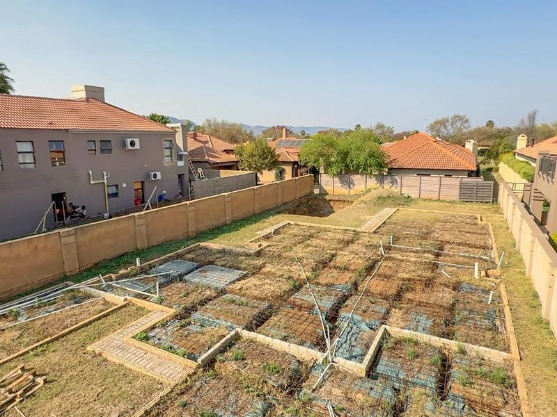 Aerial view of a residential vacant land plot featuring an unfinished foundation slab with exposed reinforcement and perimeter boundary walls.