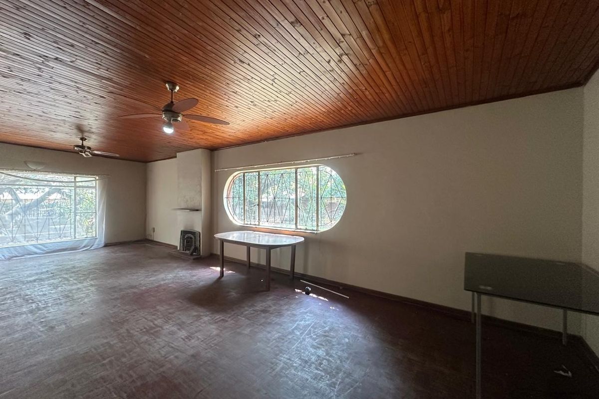 Spacious living area featuring a timber tongue and groove ceiling, parquet flooring, and a built-in fireplace with unique arched window detailing.