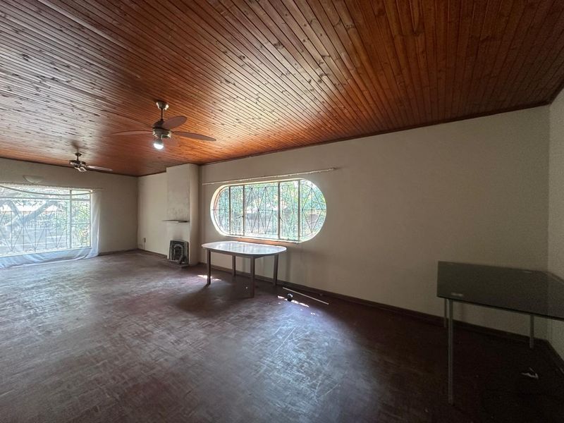 Spacious living area featuring a timber tongue and groove ceiling, parquet flooring, and a built-in fireplace with unique arched window detailing.
