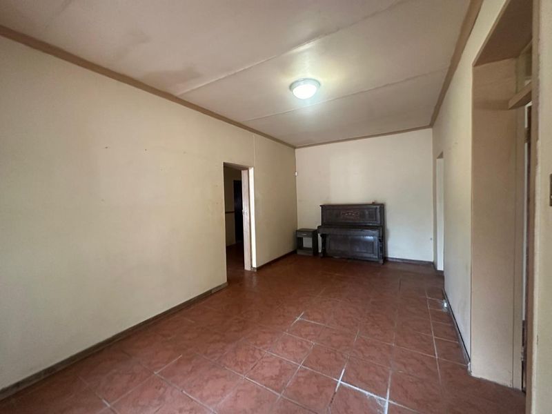 A spacious, empty living area featuring tiled flooring and neutral walls, offering a blank canvas for renovation and interior design updates.