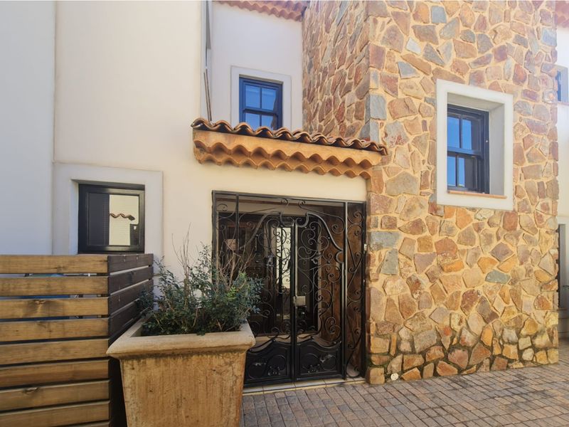 Front entrance featuring stone cladding, a decorative wrought iron security gate, and terracotta roof detailing.