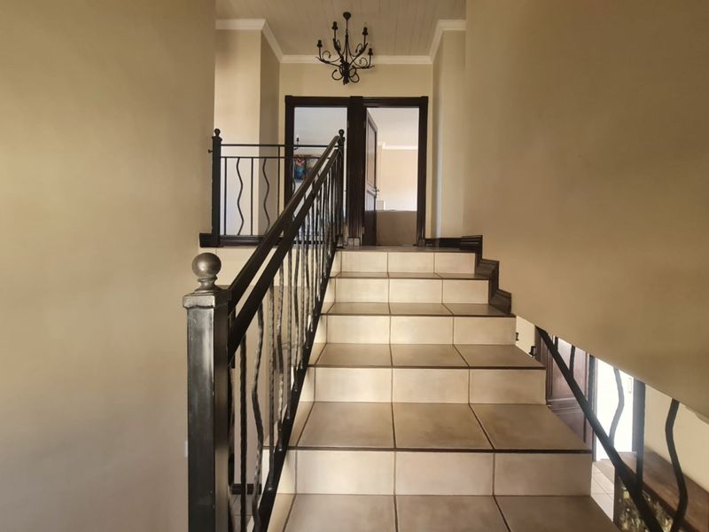 A well-maintained staircase featuring tiled steps and a decorative wrought iron balustrade, leading to an upper landing with classic architectural detailing.