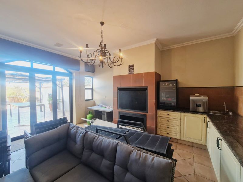 Open plan living area featuring a built-in fireplace, tiled flooring, and a functional kitchenette with granite countertops and direct access to the patio.