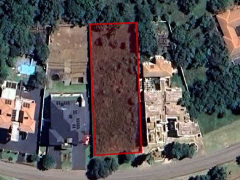 An aerial view of a vacant residential land plot situated between existing developed properties in a suburban neighborhood.