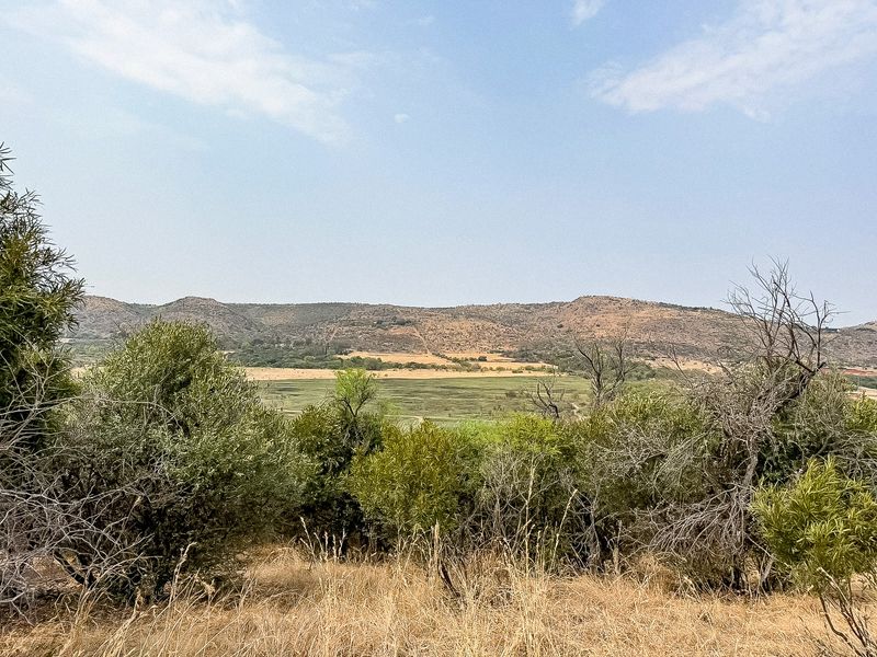 A scenic landscape view overlooking open fields and rolling hills, showcasing the natural terrain of the vacant residential land.