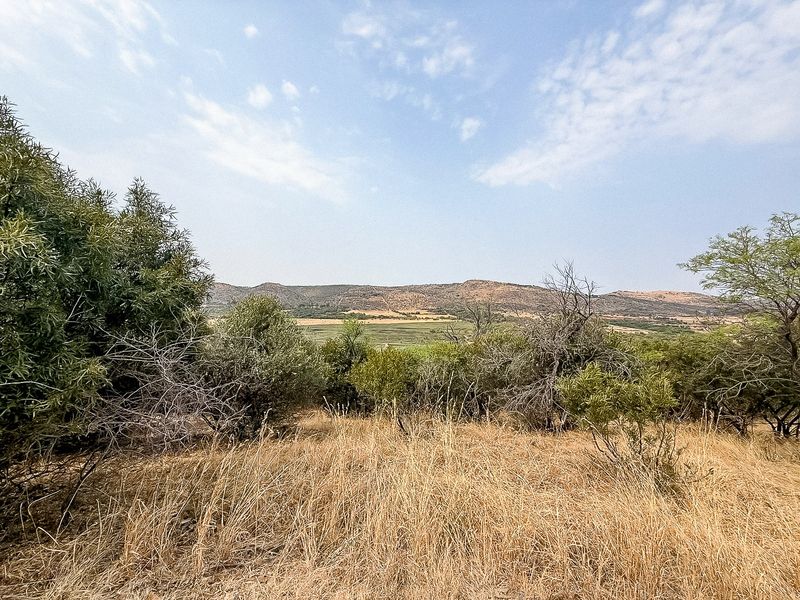 A scenic view of the surrounding landscape, featuring natural vegetation and distant hills, showcasing the property's rural setting.