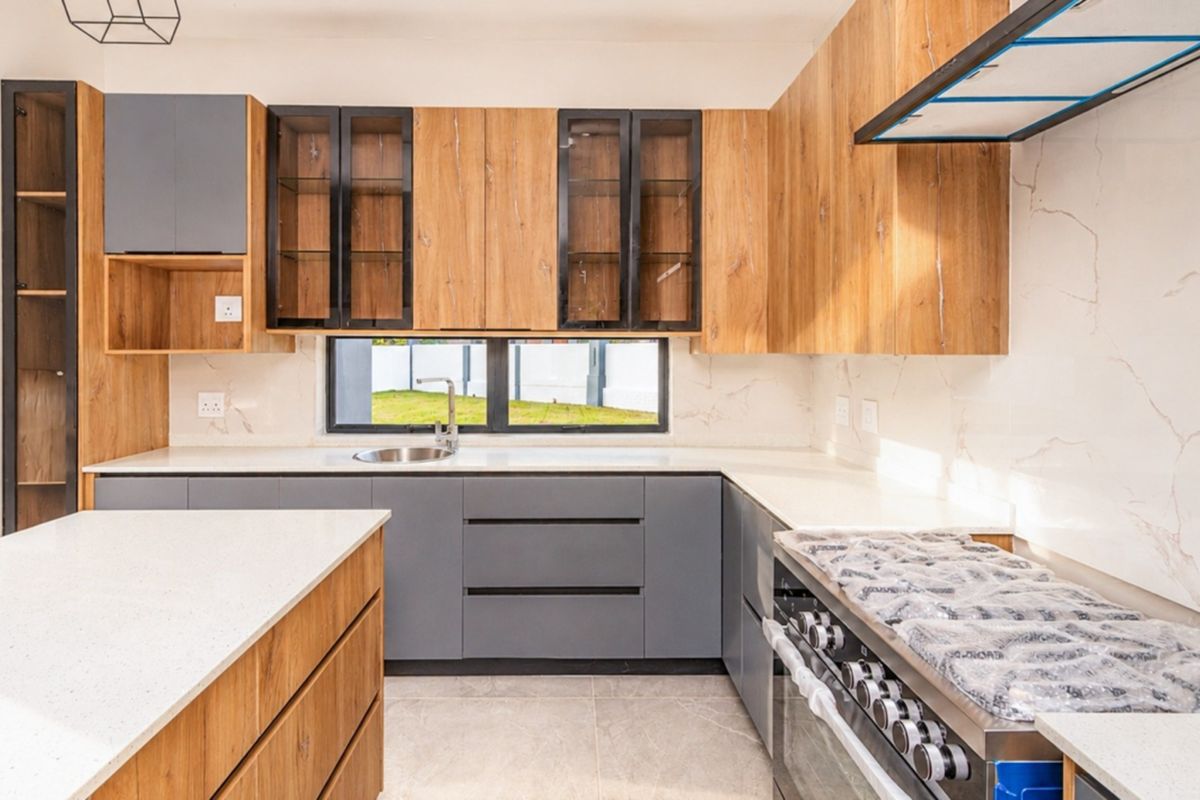 Modern kitchen featuring two-tone wood and grey cabinetry, quartz countertops, a central island, and a high-end gas stove with an integrated extractor fan.