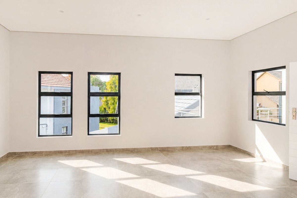 A bright, empty bedroom featuring neutral tiled flooring, modern aluminium-framed windows, and clean white walls, offering a blank canvas for personalization.