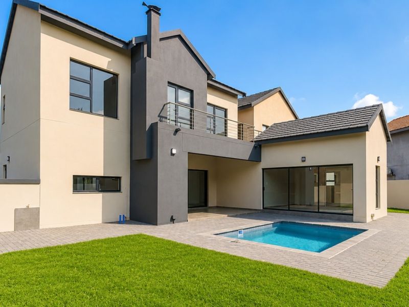 Rear view of a modern double-story house featuring a swimming pool, paved patio area, and an upper-level balcony.