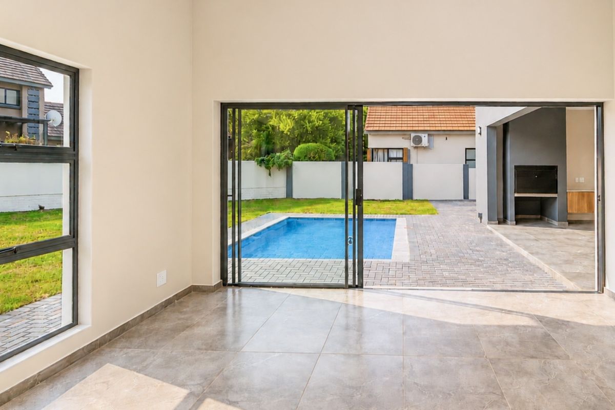 Bright, open-plan living area featuring large sliding glass doors that provide seamless access to the patio, swimming pool, and garden area.