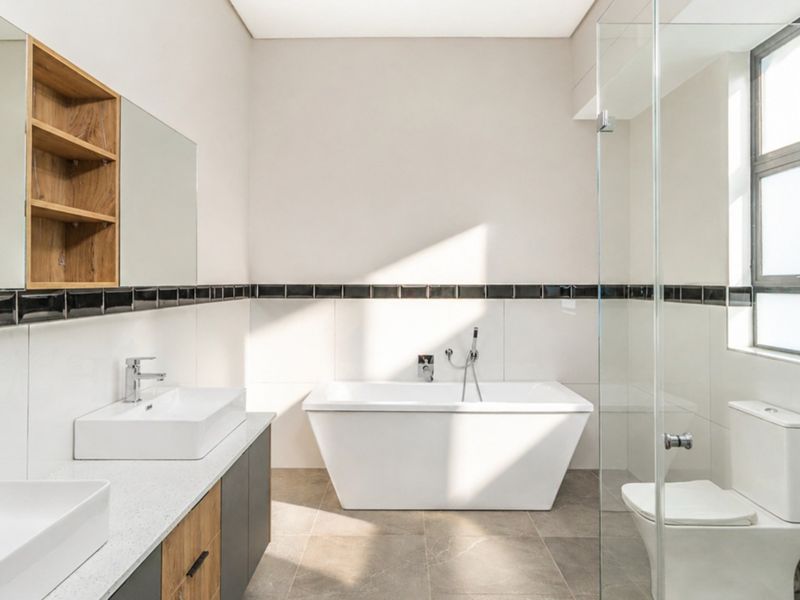 Modern bathroom featuring a double vanity, freestanding bathtub, glass-enclosed shower, and contemporary tile finishes with clean, neutral aesthetics.