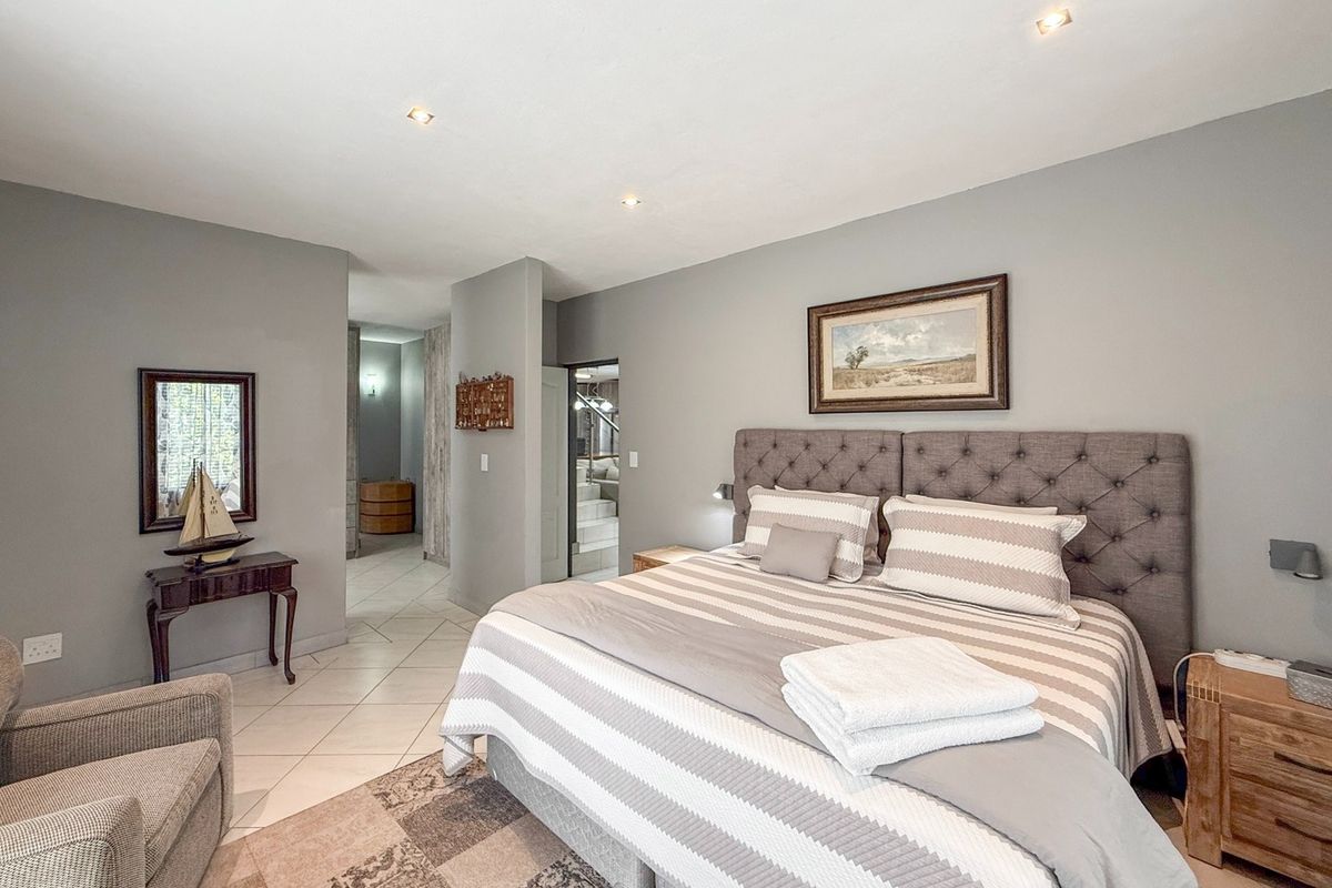 A well-maintained bedroom featuring neutral grey walls, tiled flooring, and recessed downlighting, offering a clean and comfortable living space.