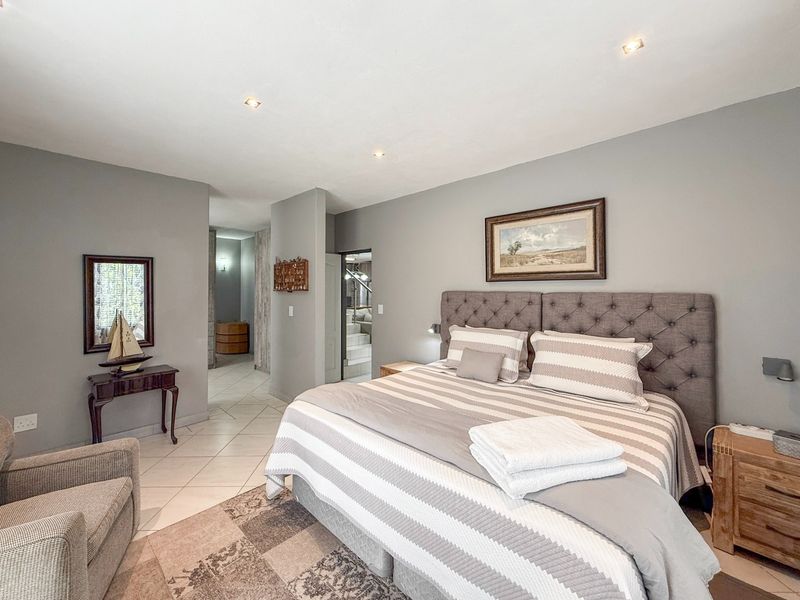 A well-maintained bedroom featuring neutral grey walls, tiled flooring, and recessed downlighting, offering a clean and comfortable living space.