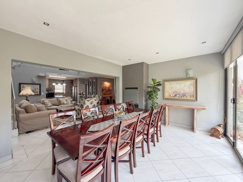Spacious open-plan dining and living area featuring tiled floors, recessed lighting, and a built-in fireplace, seamlessly connecting to the kitchen.