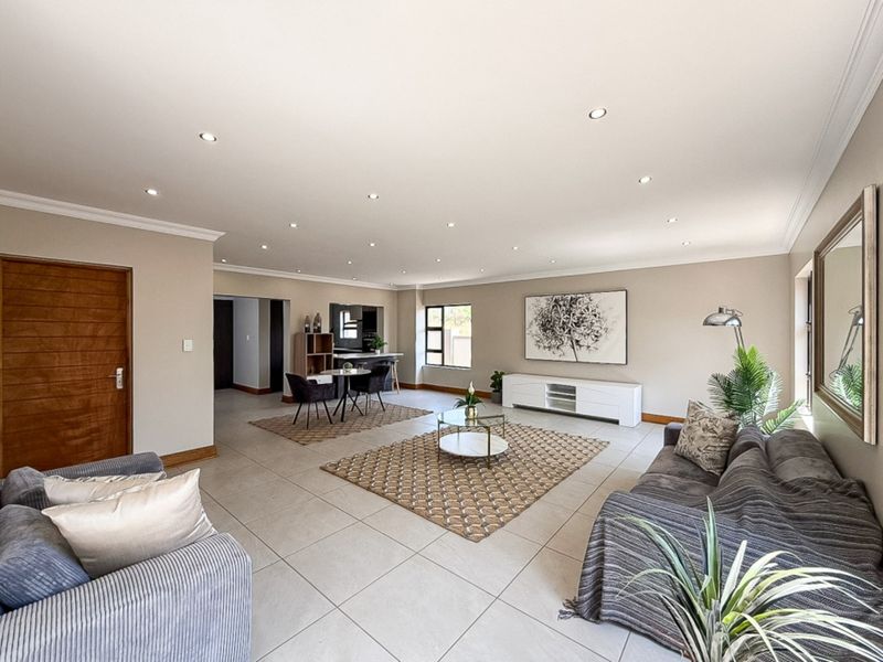 Spacious open-plan living and dining area featuring neutral tiled flooring, recessed downlighting, and a seamless flow between functional living spaces.