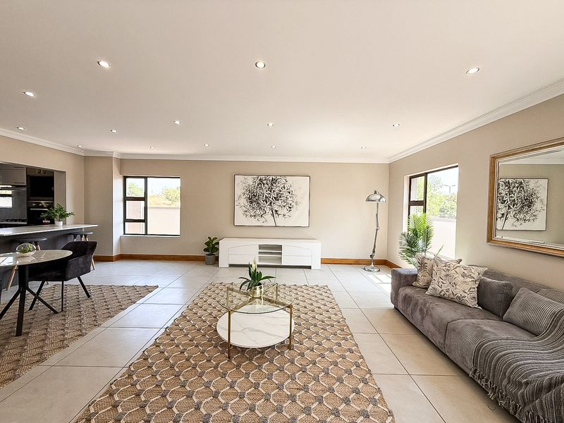 Spacious open-plan living area featuring tiled floors, recessed downlighting, and a modern kitchen island, creating a bright and functional integrated living space.