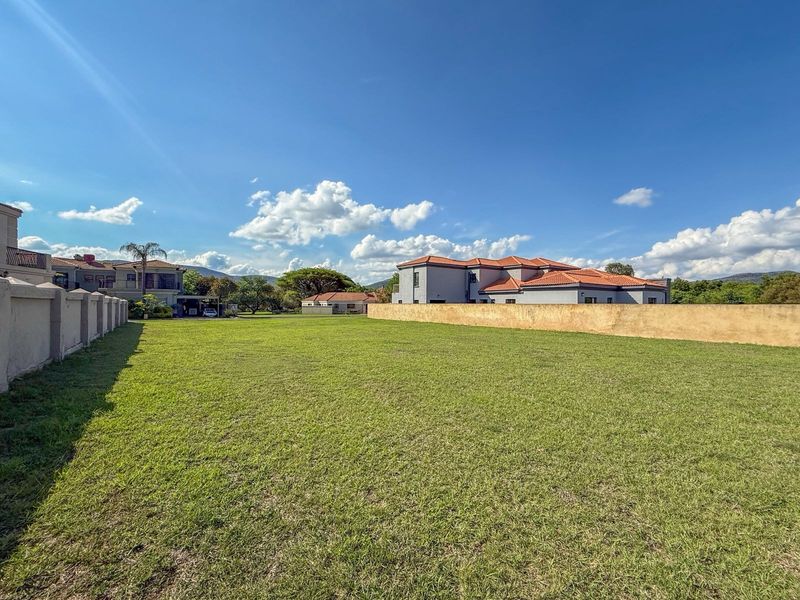A spacious, well-maintained vacant residential plot featuring a level lawn and established boundary walls in a quiet neighborhood setting.