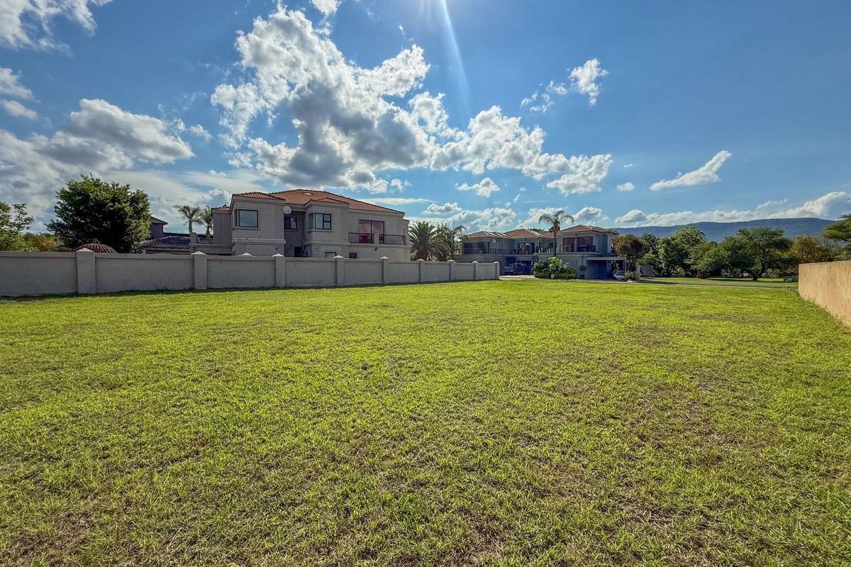 A spacious, level residential plot featuring a well-maintained lawn and perimeter boundary wall, situated in a developed neighborhood.