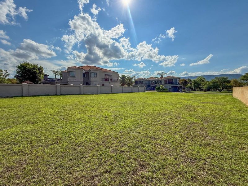 A spacious, level residential plot featuring a well-maintained lawn and perimeter boundary wall, situated in a developed neighborhood.