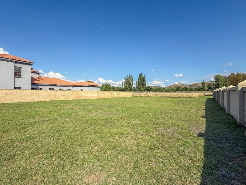 A spacious, well-maintained vacant residential plot featuring a manicured lawn and secure perimeter walling, ready for development.