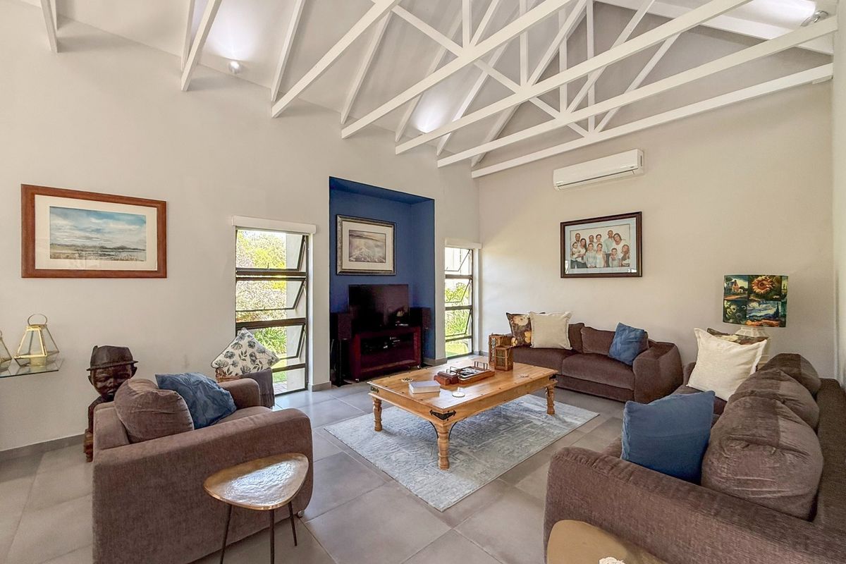 Spacious living room featuring high vaulted ceilings with exposed white trusses, large tiled floors, and a distinctive blue recessed feature wall.