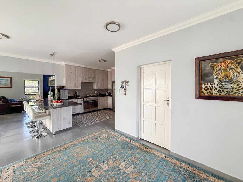Spacious open-plan kitchen and living area featuring modern cabinetry, a central island with breakfast bar, and neutral tiled flooring throughout.