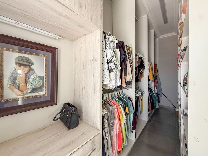 A walk-in closet or dressing area featuring extensive built-in cabinetry, shelving, and hanging storage solutions.