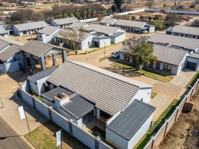 Aerial view of a retirement village complex featuring multiple residential units, paved driveways, and secure perimeter walling.