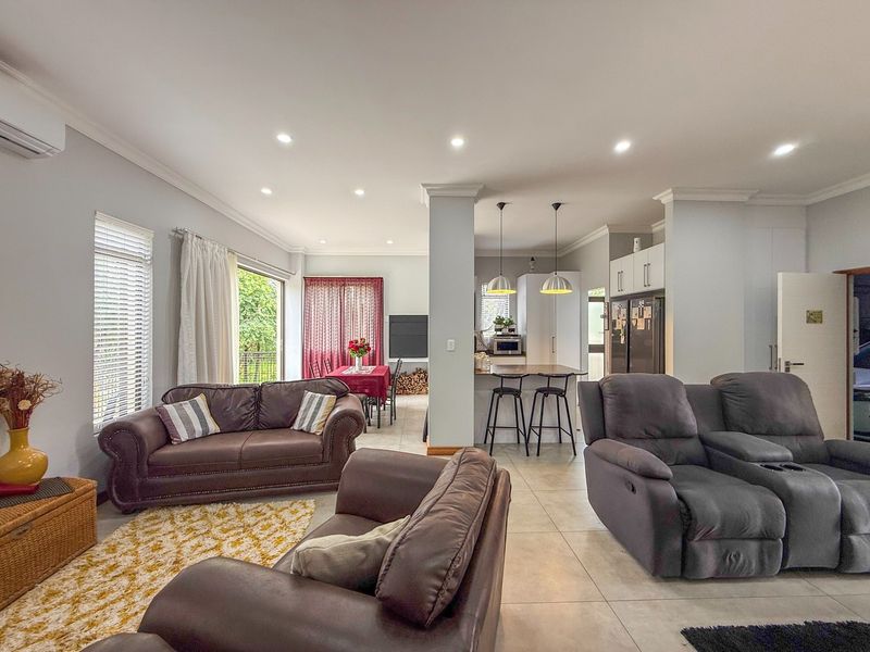 Spacious open-plan living area featuring tiled floors, recessed lighting, and a modern kitchen with an island, seamlessly connecting to the dining and lounge spaces.