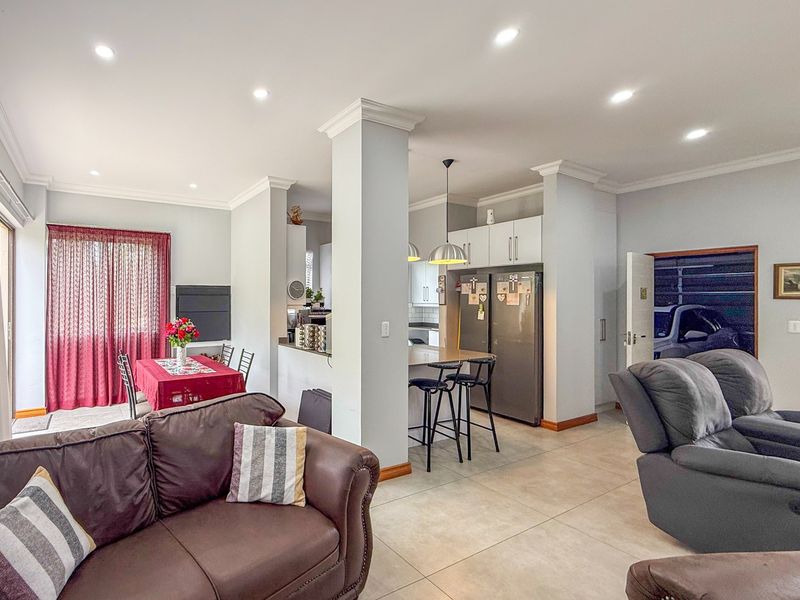 Open-plan living and kitchen area featuring tiled floors, recessed lighting, crown molding, and a functional kitchen island with breakfast bar seating.
