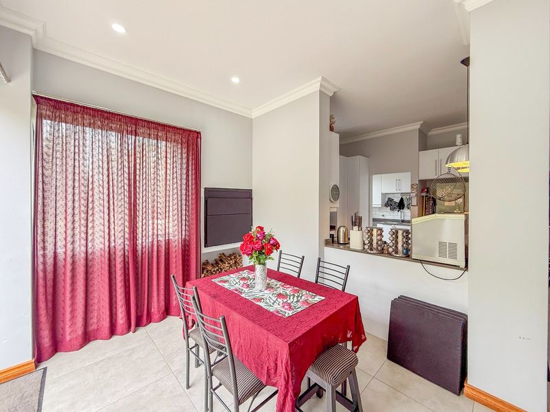 Open plan dining area featuring tiled flooring and recessed lighting, seamlessly connected to a functional kitchen with built-in cabinetry and a breakfast counter.